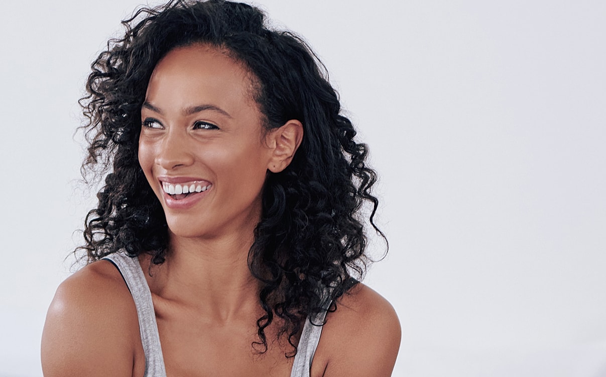 Smiling woman with curly hair and joyful expression.